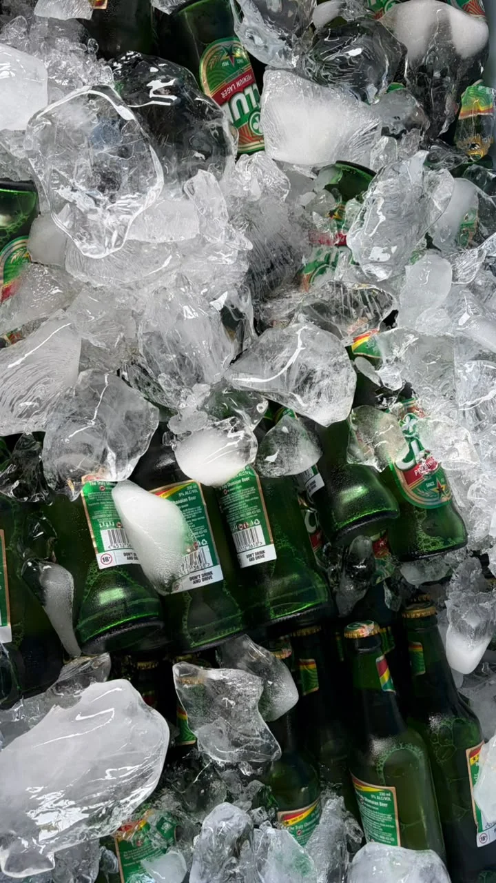 Green beer bottles nestled in chunky, glistening ice